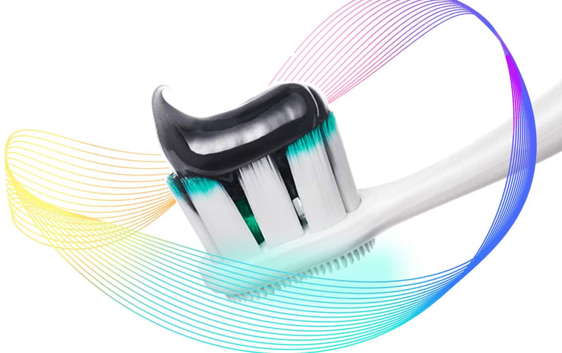 Sikat gigi Colgate Total dengan pasta pada kepala sikat, dikelilingi oleh sinar pencegahan warna-warni