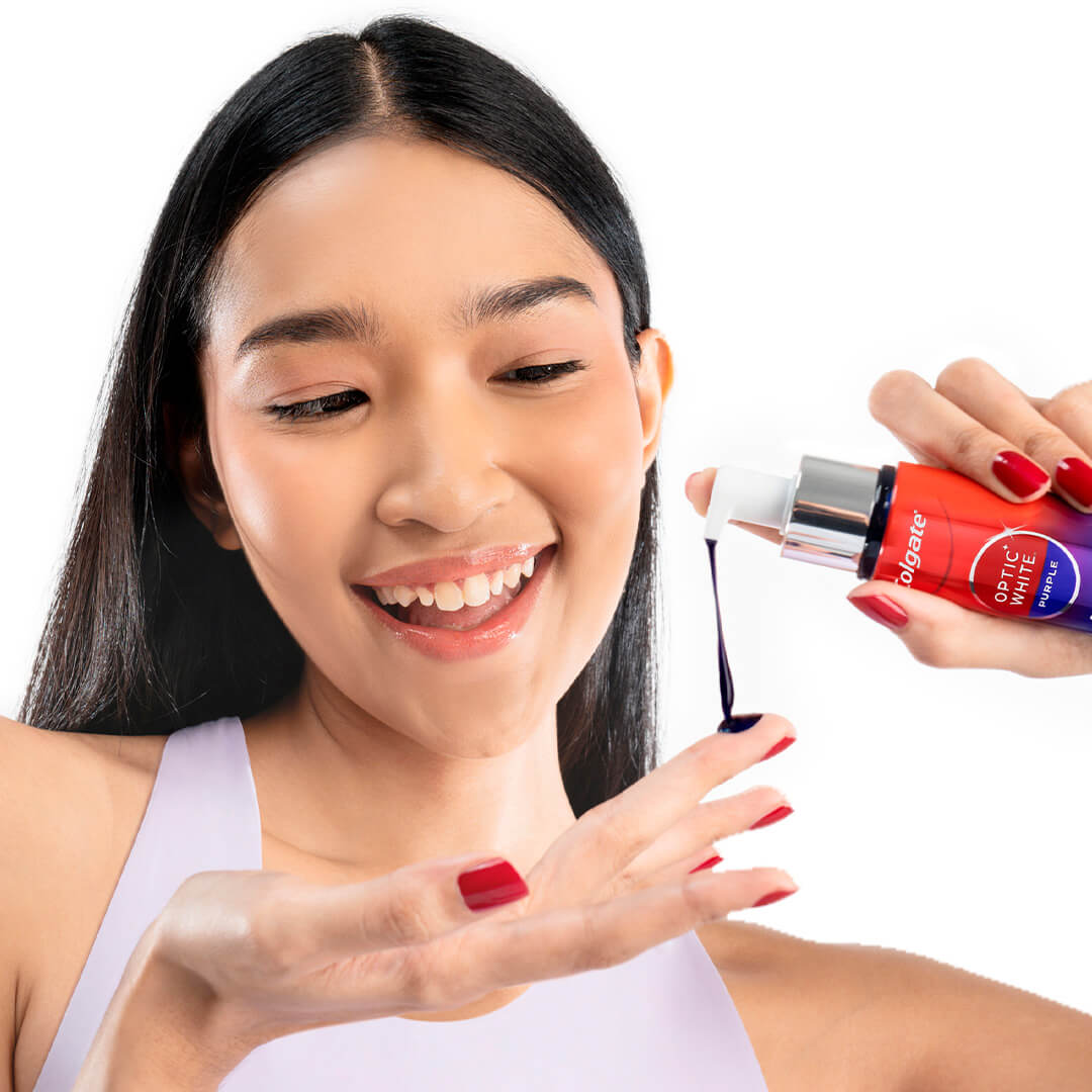 Seorang gadis muda yang tersenyum memompa Serum Purple ke jarinya dari botol