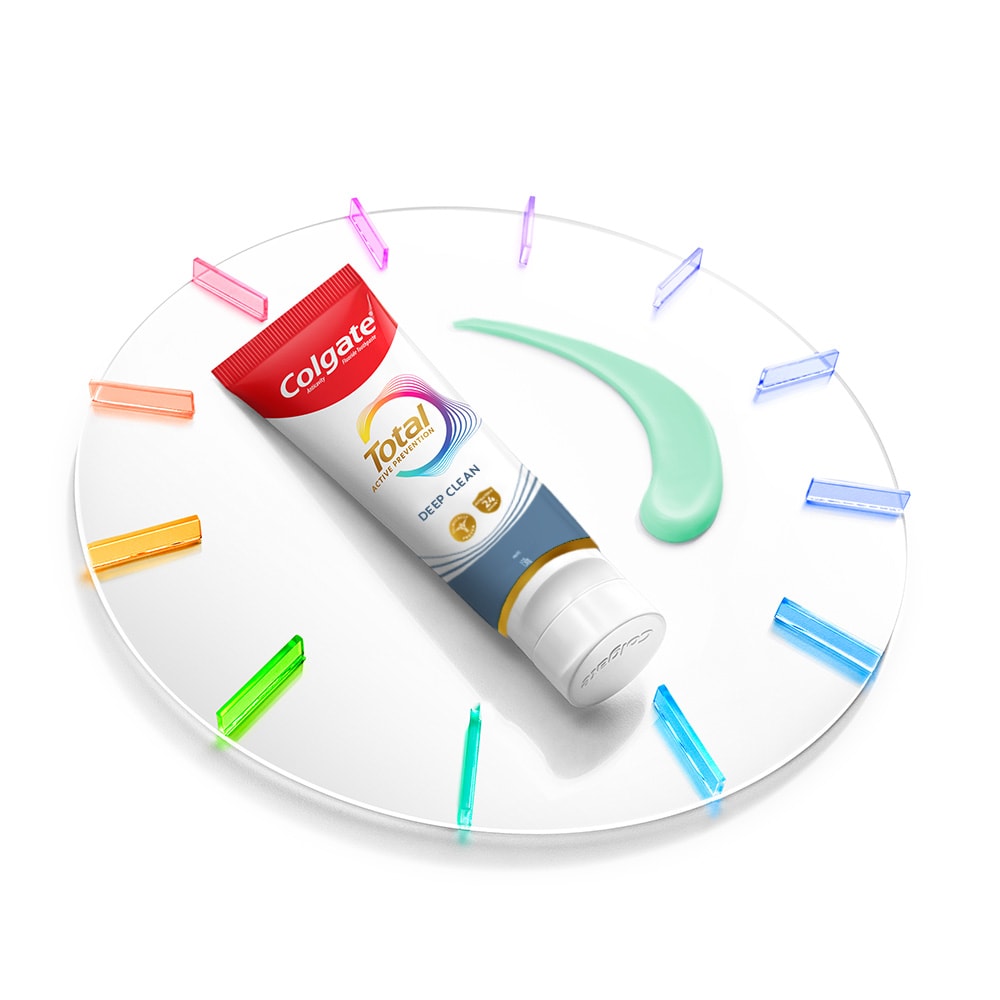 Tabung pasta gigi Colgate Total di atas jam dengan pasta di sebelahnya