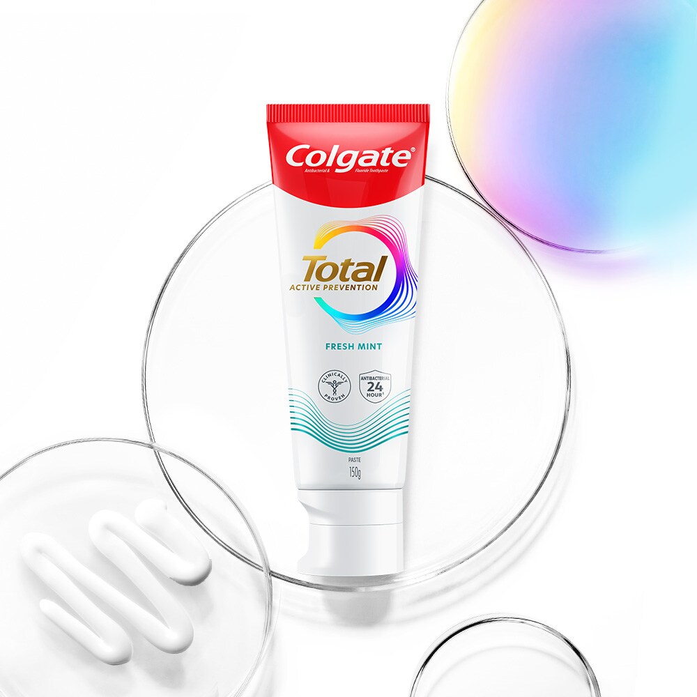 Tabung pasta gigi Colgate Total di latar depan, dengan gelembung transparan dan spektrum di latar belakang