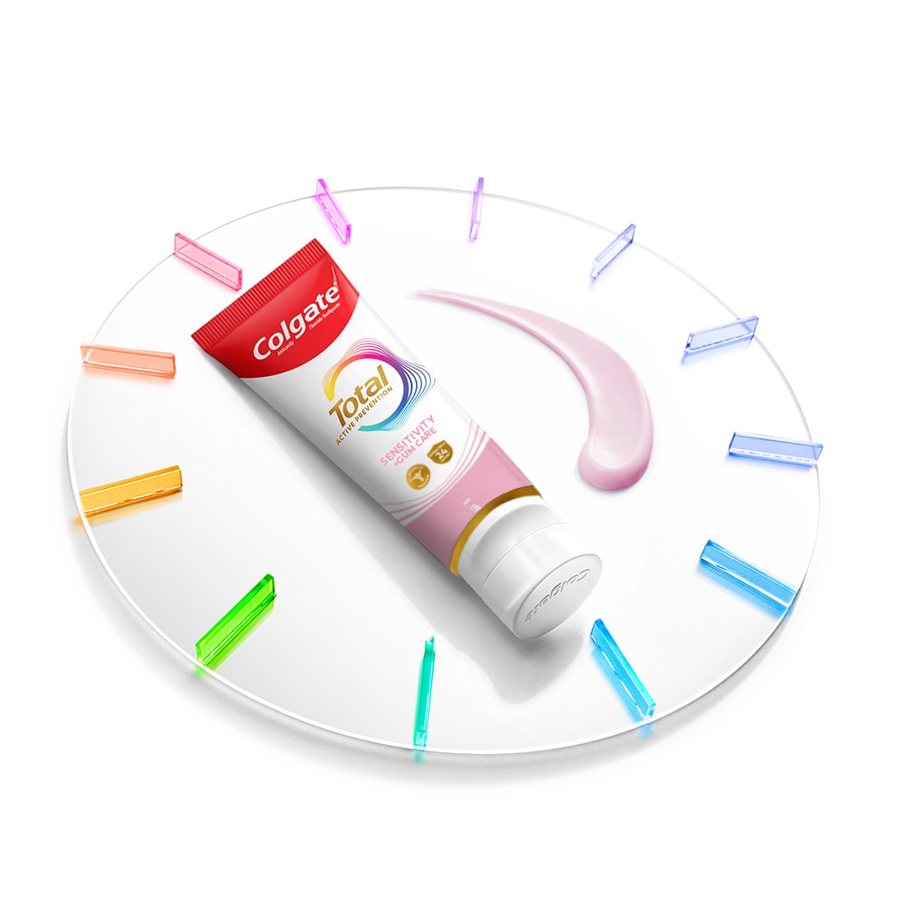 Tabung pasta gigi Colgate Total di atas jam dengan pasta di sebelahnya