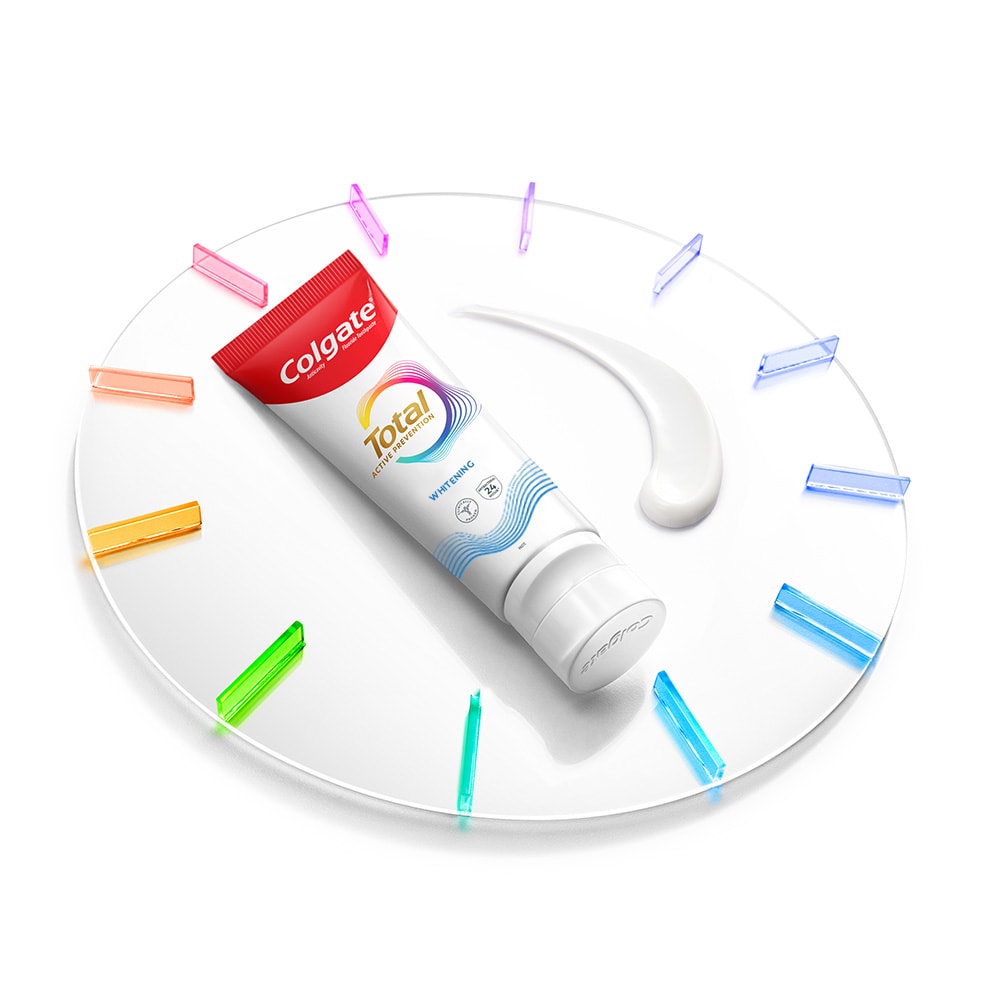 Tabung pasta gigi Colgate Total di atas jam dengan pasta di sebelahnya